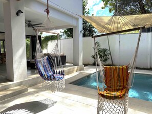 Ein Poolbereich mit zwei Hängematten, einem Deckenventilator und einem Pool.