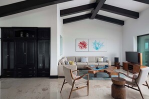A modern living room with a sofa, coffee table, and chairs, a TV, and a cabinet. - Ocean & Golf View Penthouse | Private Chef & Cart (Punta de Mita)