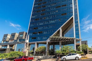 Um edifício moderno de vários andares com fachada de vidro e entrada coberta.