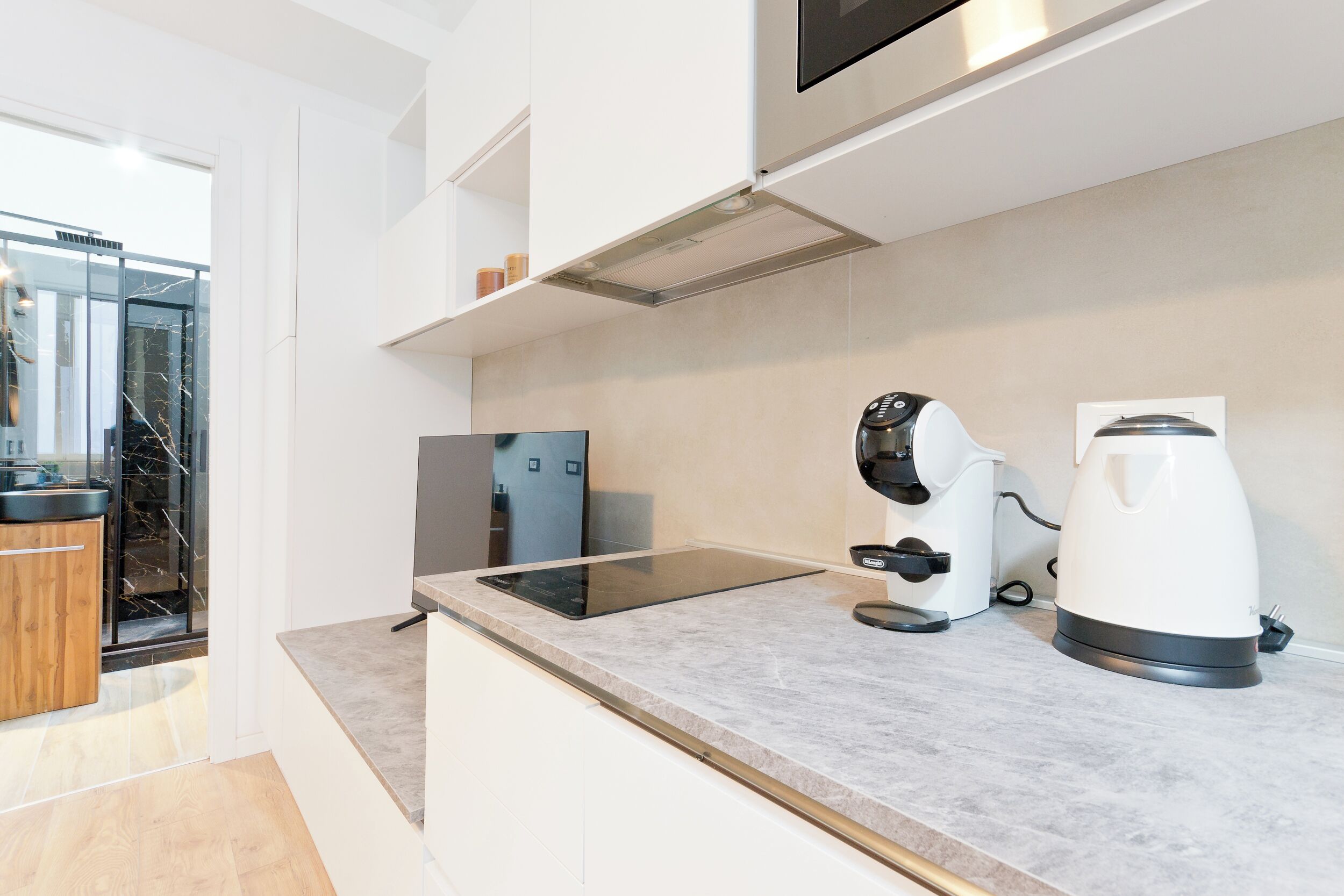 A modern kitchen with a built-in stove, a coffee maker, and a large window.