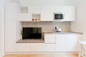 A modern kitchen with white cabinetry, a built-in microwave, a coffee maker, and a small sink. - Regina 33 - Studio Apartment, Sleeps 2 (Pescara)
