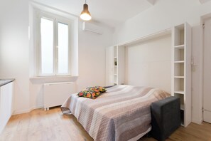 A bedroom with a bed, a window, a radiator, and built-in storage. - Regina 33 - Studio Apartment, Sleeps 2 (Pescara)