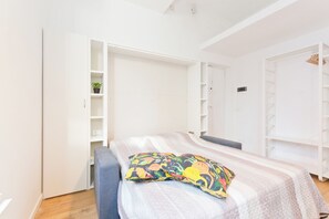 Ein Schlafzimmer mit einem Bett, einem Kleiderschrank und Regalen.