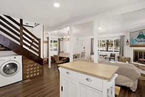 A modern hotel room with a washing machine, a wooden staircase, a dining area, and a fireplace. - Serenity Peak Big Bear Lake, Family & Groups Mountain Getaway (Big Bear Lake)