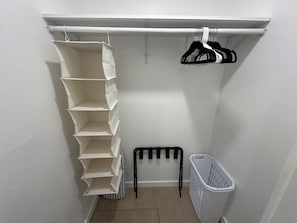 Ein Waschbereich mit weißer Wand, einer Wäscheständer, einem Wäschekorb und einer Trittleiter.