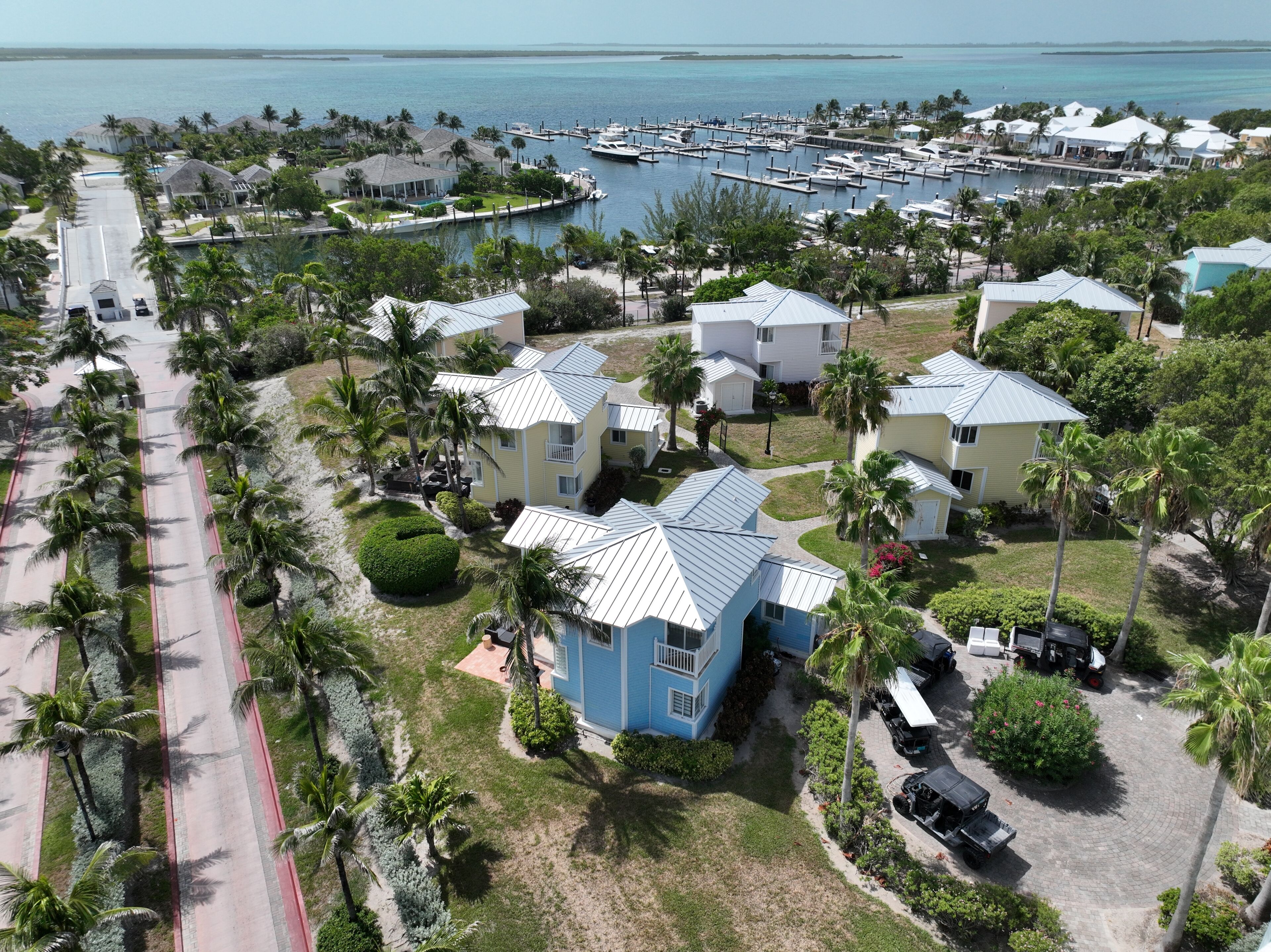 A coastal residential area with multiple houses, a marina, and a road.