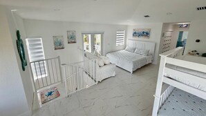 Un dormitorio amplio con una cama grande, una escalera y vistas al exterior.