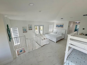 Un dormitorio amplio con una cama grande, una escalera y vistas al exterior.