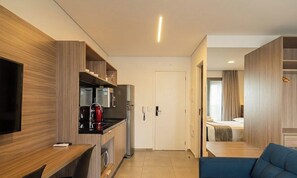 A modern hotel room with a kitchenette, a TV, a sofa, and a bed. - Comfort in Condo. w/ Pool & Balcony Plt0086 (São Paulo)