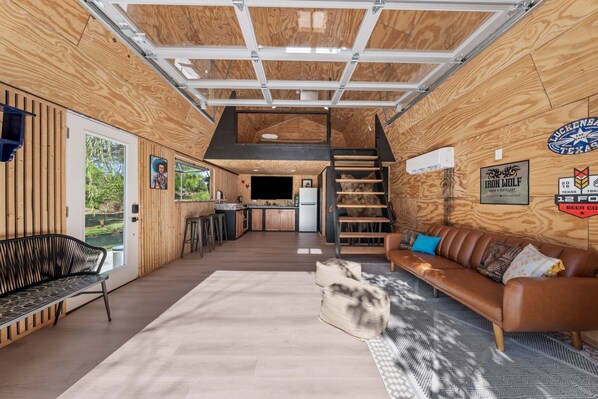 Un interior amplio con cocina, comedor y una escalera que conduce a un nivel superior.