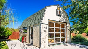 Een laag, enkelvoudig gebouw met een grote garageklep, een schuin dak en een klein raam.