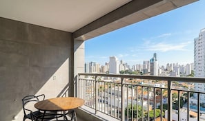 A balcony with a table and chairs, overlooking a cityscape with high-rise buildings. - Comfort in Condo. w/ Pool in Tatuape Plt0115 (São Paulo)