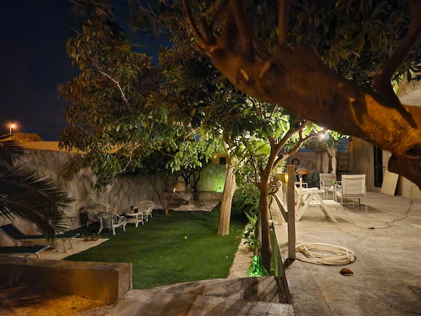 An outdoor patio area with a lawn, seating, and a tree.