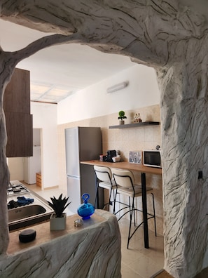 A modern kitchen with a marble island, a built-in stove, and a refrigerator.