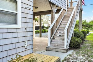 A wooden staircase leading to a covered porch with a bench and a small table.