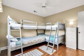 A bunk bed room with a ceiling fan, a dresser, and a door. - SURF AND SOUND- Enjoyable 3-bedroom house with AC in Topsail Beach (Topsail Beach)