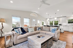 A spacious living room with a sectional sofa, a coffee table, and a view of the kitchen.
