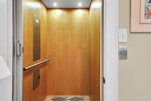 An elevator with a wooden interior, a handrail, and a control panel. - SURF AND SOUND- Enjoyable 3-bedroom house with AC in Topsail Beach (Topsail Beach)