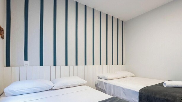 A hotel room with two beds, a striped wall, and a white ceiling. - Apt. w/ Balcony 200m From Bacutia Beach Mfa0409 (Guarapari)