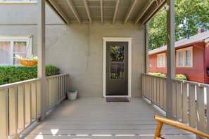 A covered porch with a door, potted plants, and a bench. - Charming 3-bedroom house in Tulsa with cool AC and comfort (Tulsa)