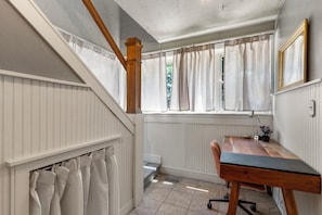 A room with a wooden desk, a window with curtains, a radiator, and a mirror on the wall. - Charming 3-bedroom house in Tulsa with cool AC and comfort (Tulsa)