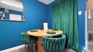 A room with a round wooden table, green upholstered chairs, a mirror, and a green curtain. - Grand Teal King Suite,Fireplace,Pool,Movie Theaters,Beach (Gulfport)
