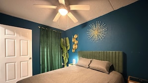 A bedroom with a bed, a ceiling fan, a wall clock, and a decorative wall piece. - Grand Teal King Suite,Fireplace,Pool,Movie Theaters,Beach (Gulfport)