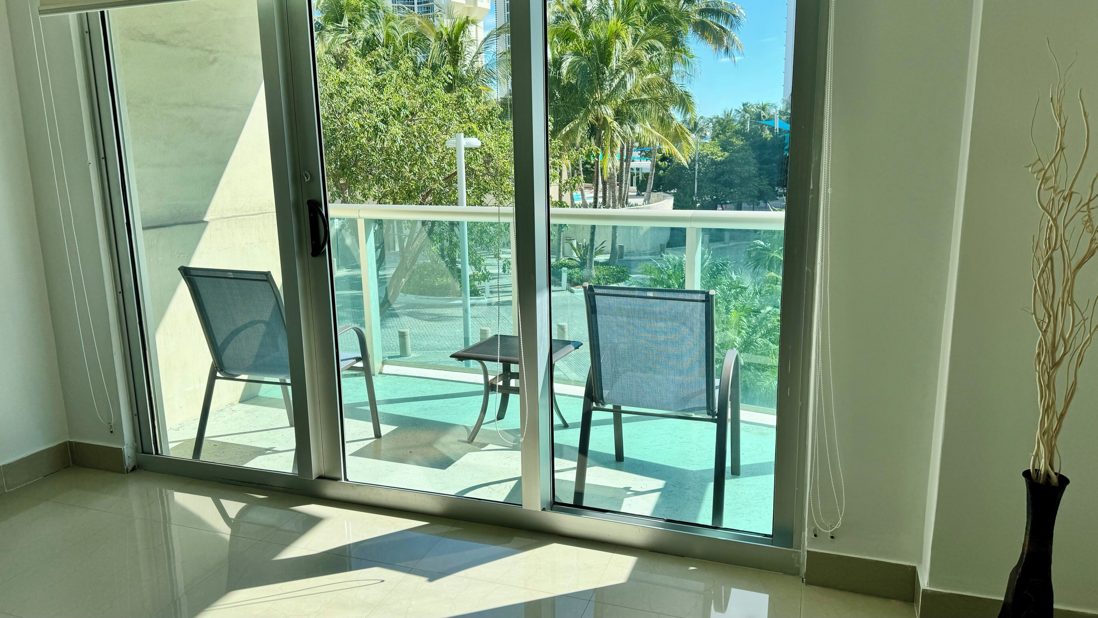 A room with a large sliding glass door leading to an outdoor area with chairs and a table.