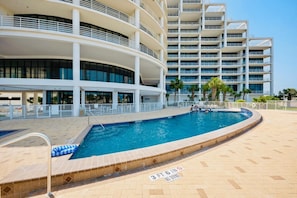Un espace piscine comprenant une piscine, un panneau indiquant une profondeur minimale de 1,1 mètre (3 pieds et 6 pouces) et interdisant les plongeons, ainsi qu’un immeuble à plusieurs étages doté de balcons.