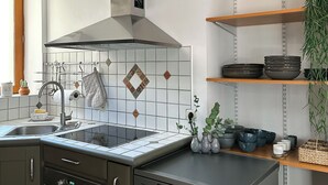 A modern kitchen with a stainless steel range hood, a built-in dishwasher, and a window above the sink.