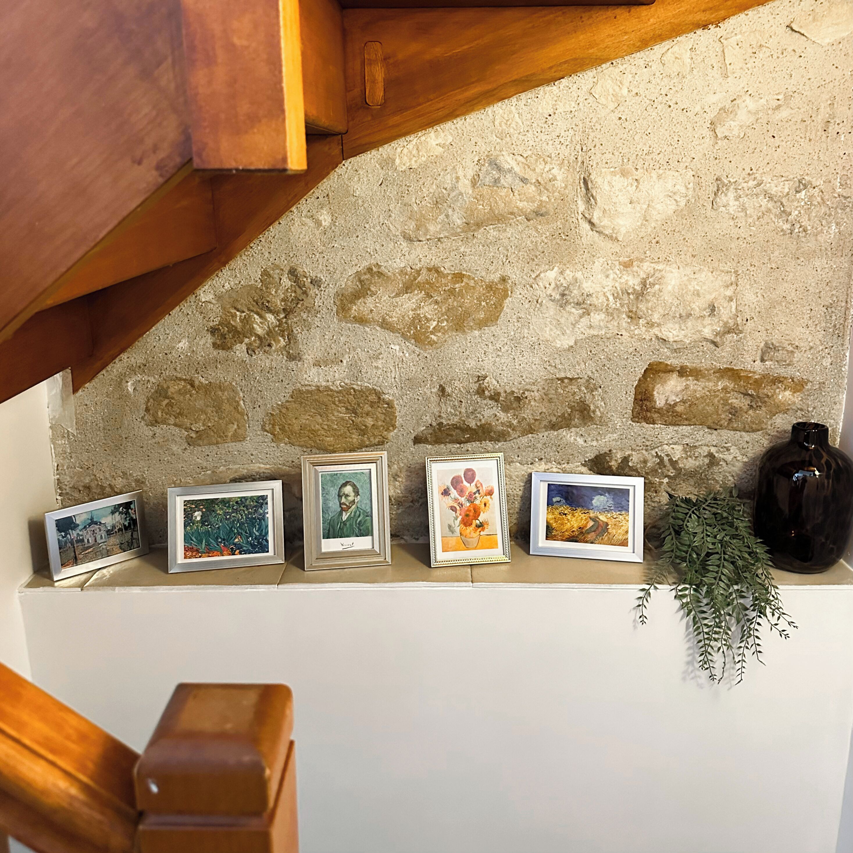 A shelf with framed artworks and a vase.