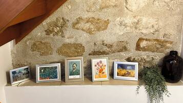 A shelf with framed artworks and a vase.