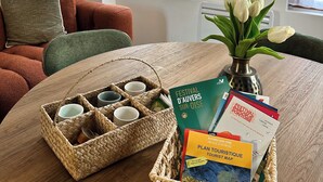 A room with a wooden table, a wicker basket with cups, a vase with white flowers, and a tourist map.