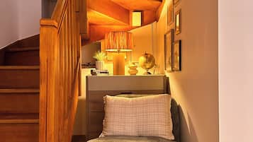 Ein gemütliches Zimmer mit einer Holztreppe, einem bequemen Sessel, einem kleinen Hocker und einem Schreibtisch mit Globus und Büchern.