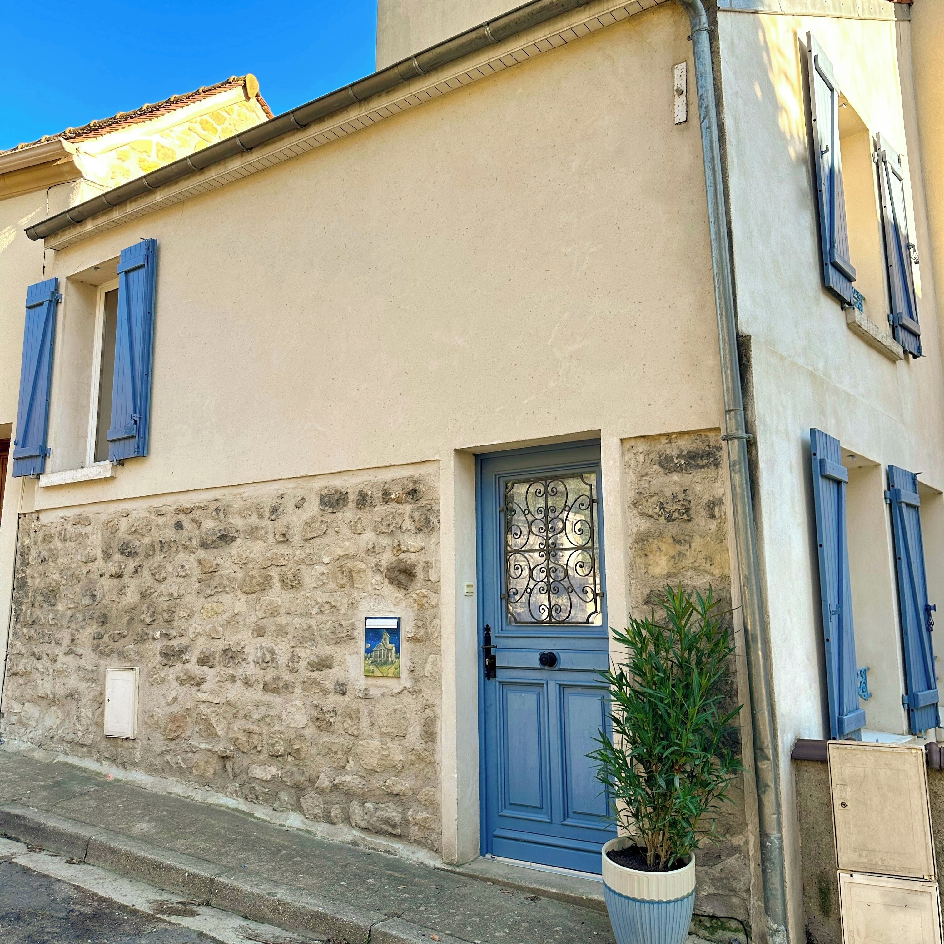 A building with a blue door, stone wall, and blue shutters.