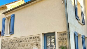 A building with a blue door, stone wall, and blue shutters.