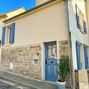 A building with a blue door, stone wall, and blue shutters.