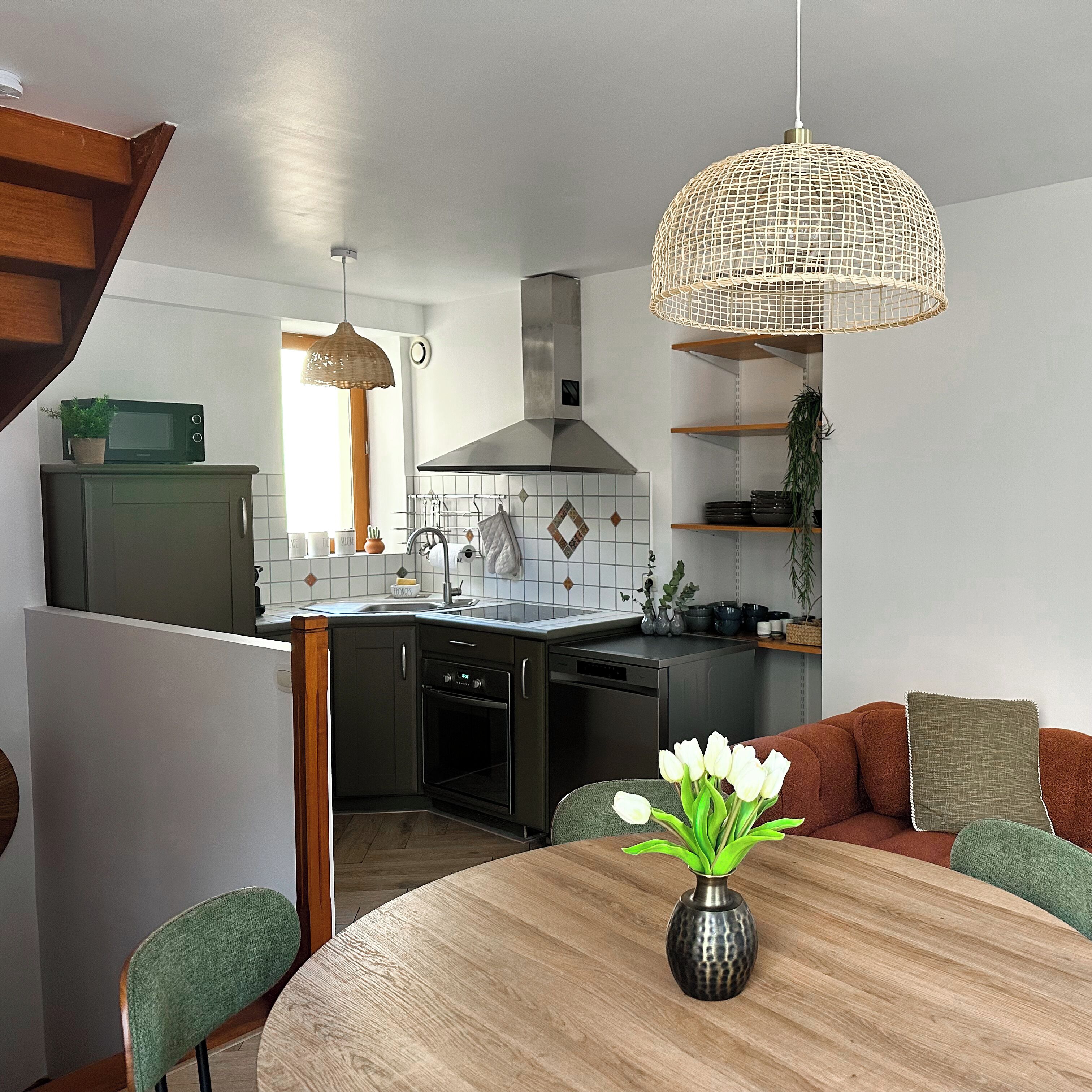 Et moderne køkken med spiseplads, inklusive et rundt bord med en vase blomster.