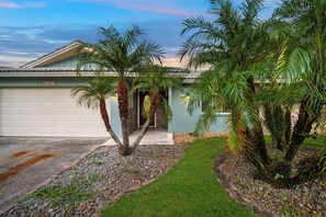 A residential property with a garage, palm trees, and a well-maintained lawn.