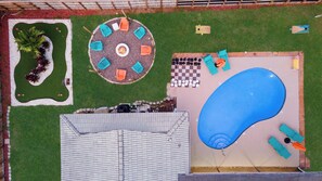 A rooftop pool area with a circular seating arrangement, a checkered game table, and a large blue pool.