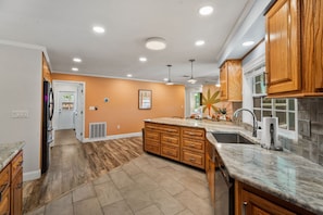 A modern kitchen with wooden cabinets, a marble countertop, and a central island.