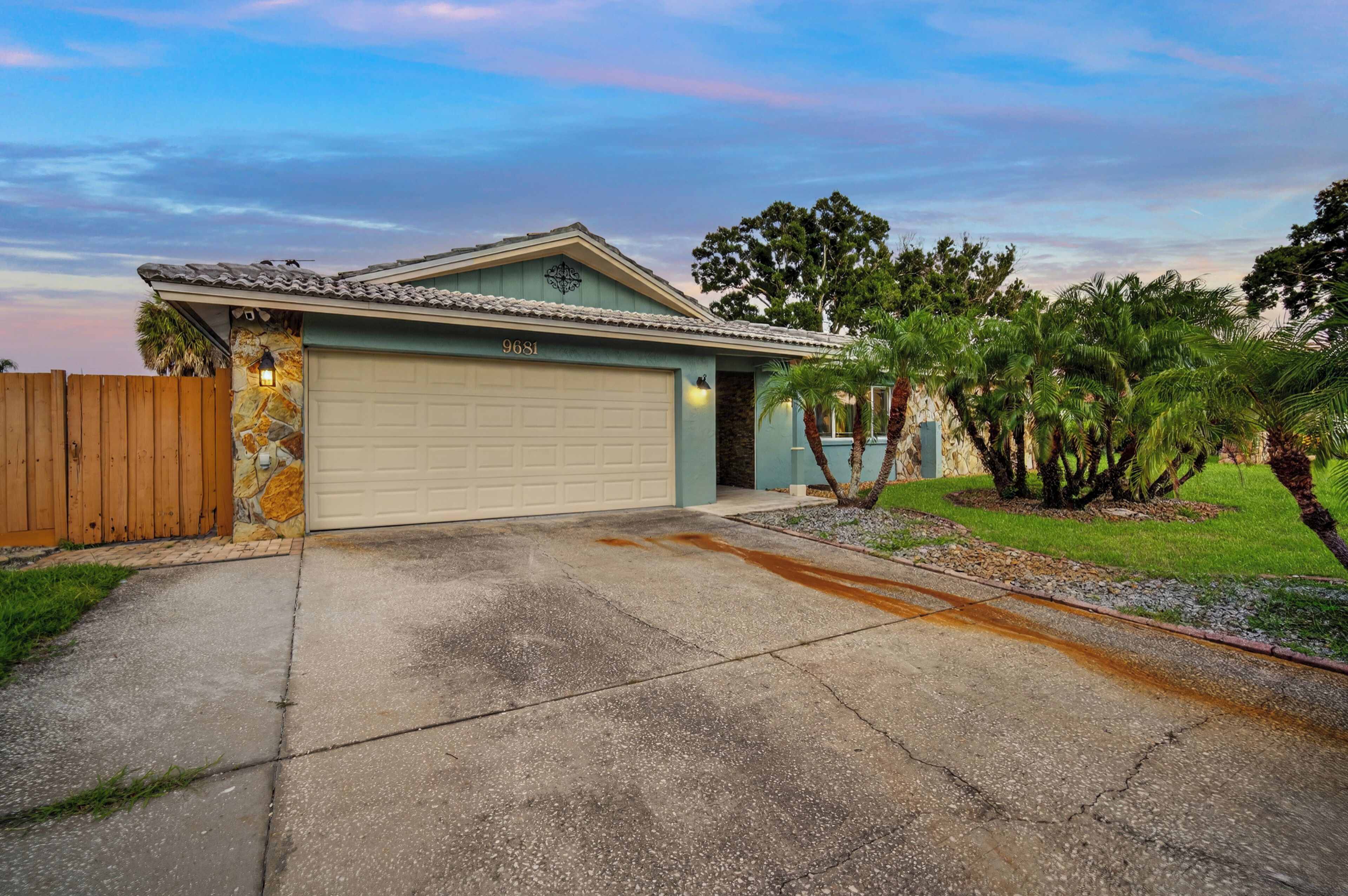 A single-story house with a garage, a stone facade, and a number '9681' on the garage door.