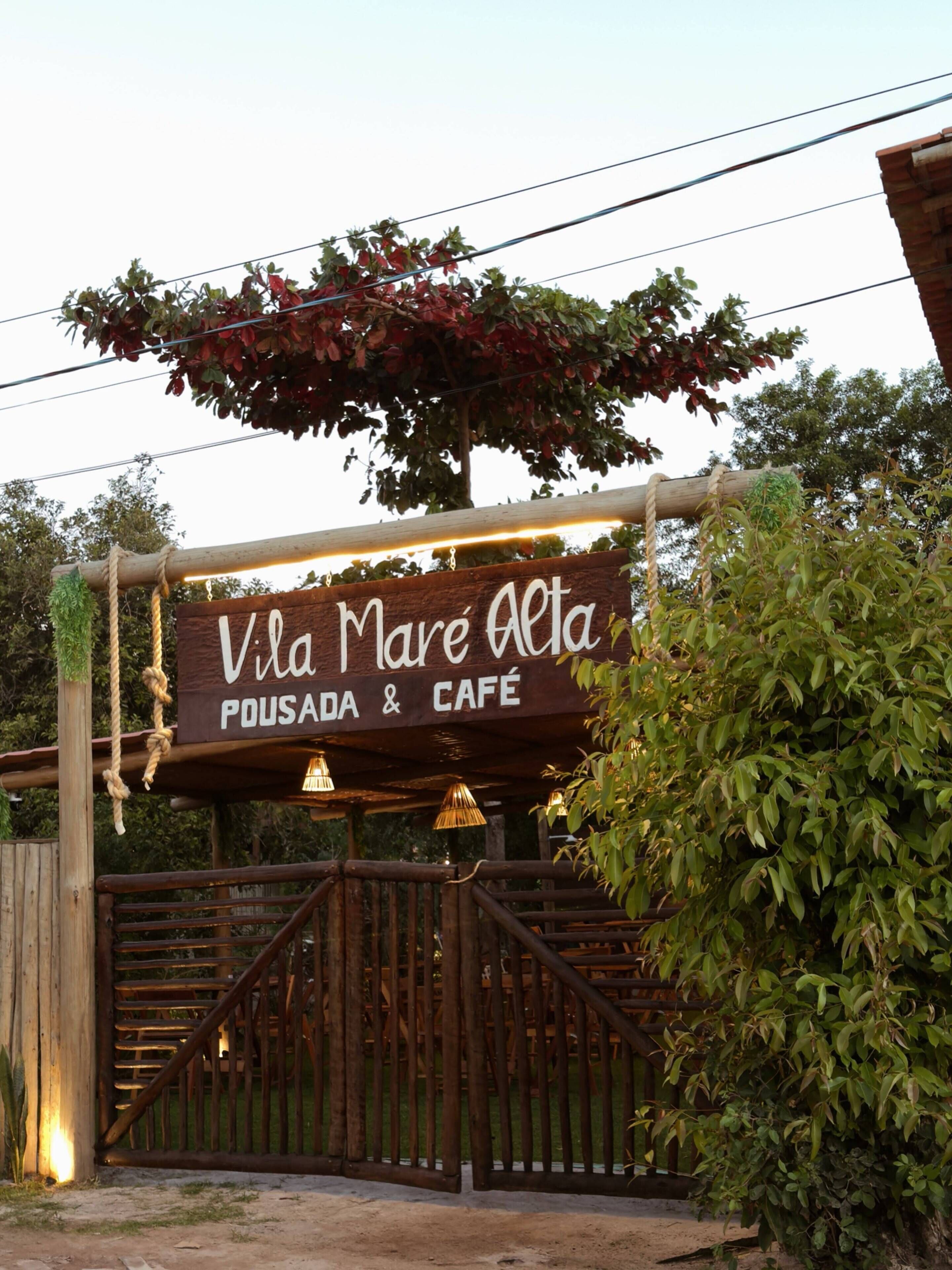Un cartello in legno per Vila Mare Alta Pousada & Cafe, con un cancello rustico e una barriera di corda.