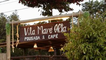 Un cartello in legno per Vila Mare Alta Pousada & Cafe, con un cancello rustico e una barriera di corda.