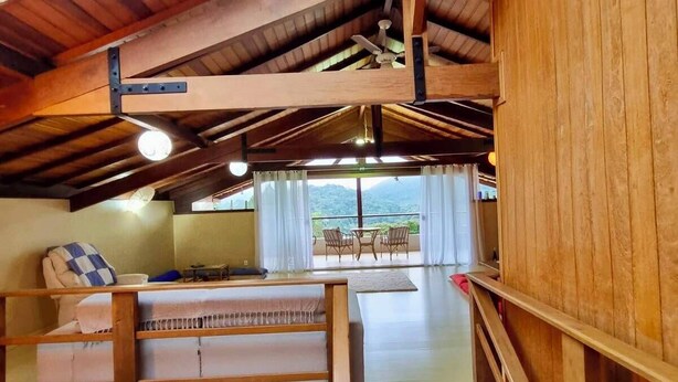 Una habitación con techo de madera, una cama, un sofá y vistas al exterior.