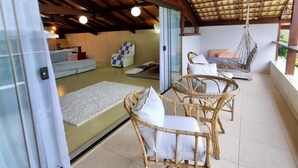 Un espacio de estar al aire libre cubierto con muebles de mimbre y una silla colgante.