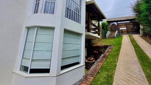 Un edificio en esquina con fachada blanca, terraza de madera y sendero de ladrillo.