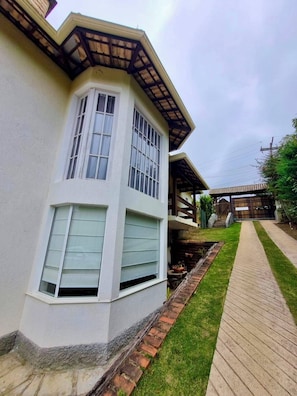 Un edificio en esquina con fachada blanca, terraza de madera y sendero de ladrillo.