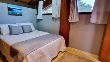 Quarto com cama, um quadro e janela com cortinas.