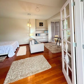Un dormitorio con cama, sofá, estantería y ventana.